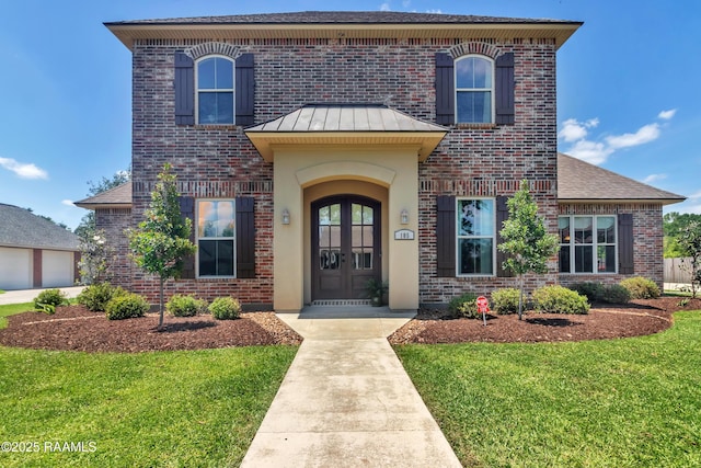 traditional-style home featuring brick siding, a front lawn, french doors, and a standing seam roof
