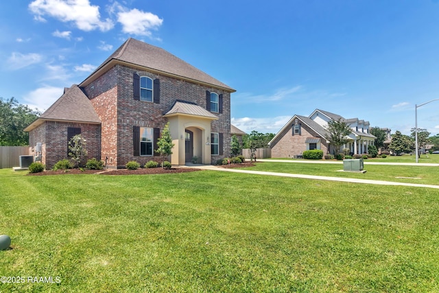 view of front facade with fence, a front yard, a standing seam roof, brick siding, and central air condition unit