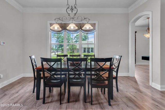 dining area featuring crown molding, arched walkways, baseboards, and wood finished floors