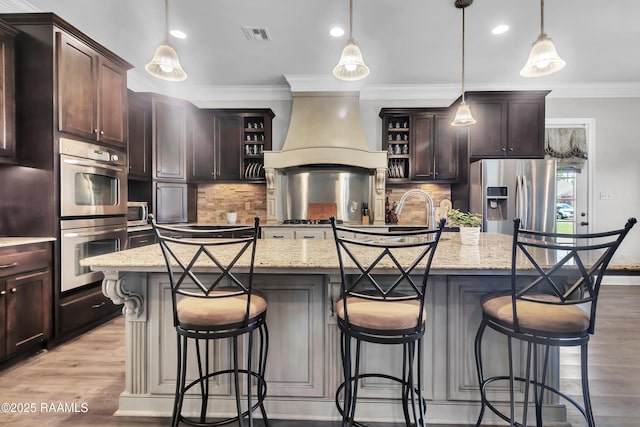 kitchen featuring crown molding, dark brown cabinets, open shelves, appliances with stainless steel finishes, and premium range hood