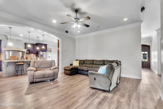 living room featuring recessed lighting, arched walkways, light wood-style flooring, and a ceiling fan