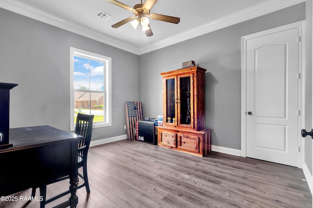 office featuring crown molding, ceiling fan, baseboards, wood finished floors, and visible vents