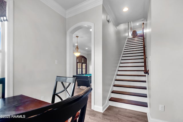 stairway featuring crown molding, wood finished floors, baseboards, pool table, and arched walkways