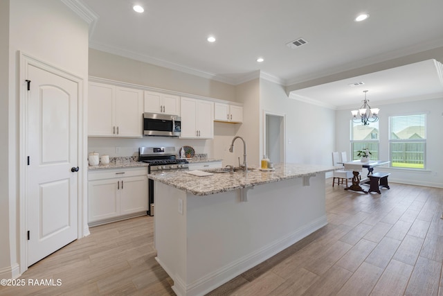 kitchen featuring a sink, light wood-style flooring, stainless steel appliances, white cabinetry, and visible vents