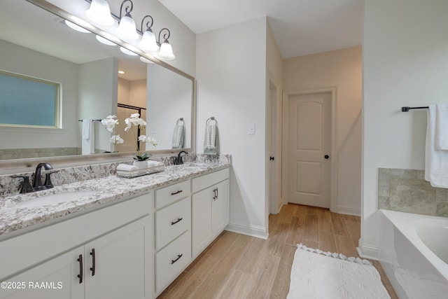 bathroom with baseboards, a sink, a bathing tub, and wood finished floors