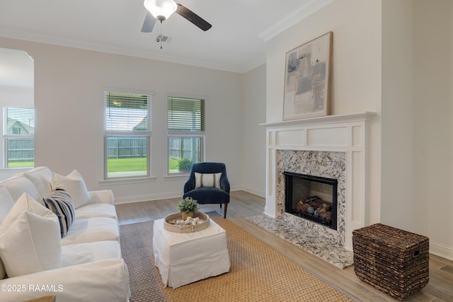 living room with crown molding, a ceiling fan, wood finished floors, and a fireplace