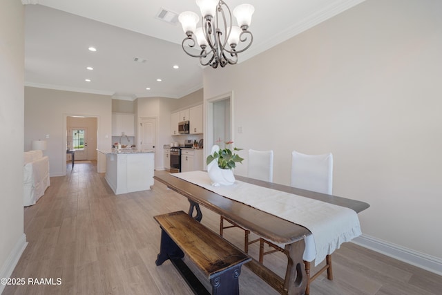 dining room featuring crown molding, recessed lighting, light wood-style flooring, and a chandelier