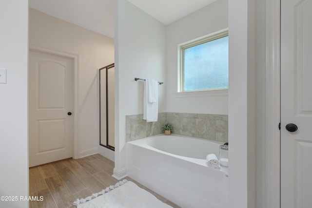 full bath with a garden tub, baseboards, wood finished floors, and a shower stall