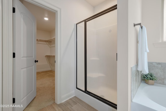 full bathroom with recessed lighting, a shower stall, wood finished floors, a spacious closet, and a bath