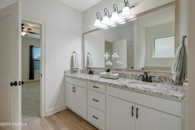 bathroom with double vanity, baseboards, a sink, and wood finished floors
