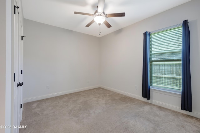 empty room with a ceiling fan, baseboards, and light colored carpet