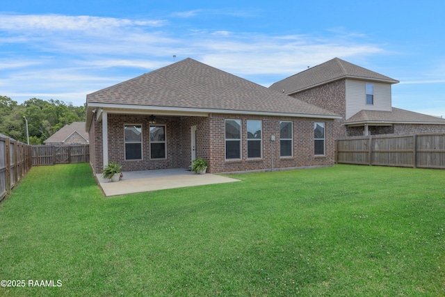 back of house with a lawn, brick siding, a fenced backyard, and roof with shingles