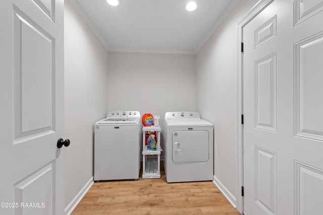 washroom with washing machine and dryer, light wood-type flooring, ornamental molding, and laundry area