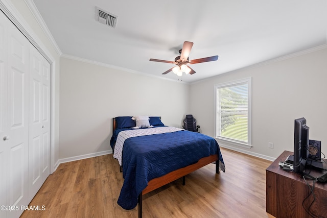 bedroom with light wood-type flooring, visible vents, baseboards, and ornamental molding