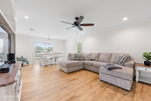 living area featuring crown molding, light wood-type flooring, visible vents, and a ceiling fan