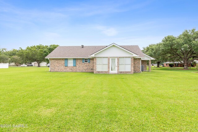 ranch-style home featuring a front lawn, a shingled roof, brick siding, and cooling unit