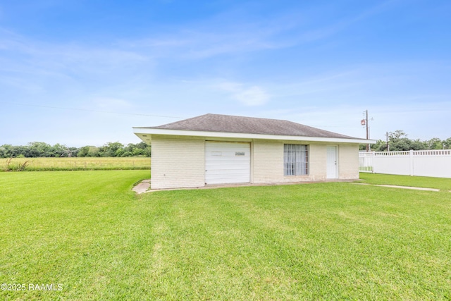 rear view of property featuring fence, brick siding, and a lawn