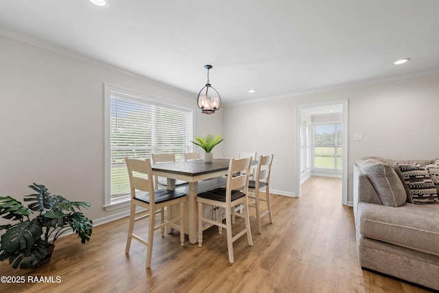 dining area with a notable chandelier, ornamental molding, and light wood-type flooring