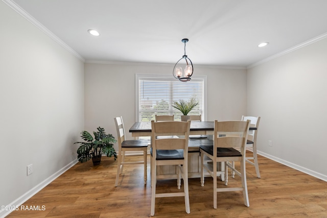 dining area with ornamental molding, a notable chandelier, and light wood-style flooring