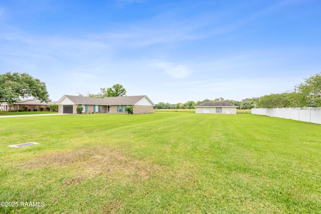view of yard featuring driveway, a garage, and fence