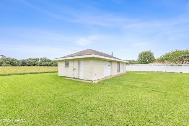 exterior space featuring a lawn, an outbuilding, brick siding, and fence