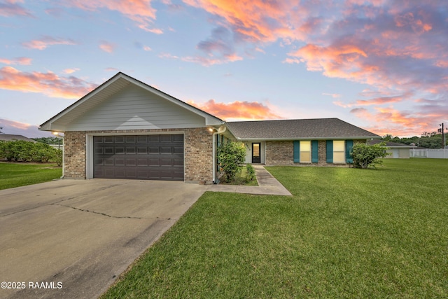view of front of property featuring concrete driveway, a front lawn, brick siding, and an attached garage