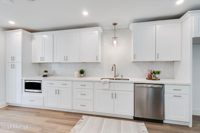 kitchen with light countertops, white cabinetry, stainless steel appliances, and a sink
