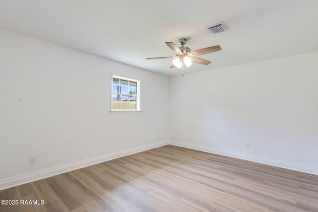 spare room with baseboards, light wood-style floors, visible vents, and ceiling fan