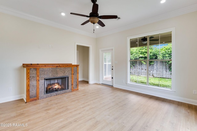 unfurnished living room with a ceiling fan, a fireplace, wood finished floors, baseboards, and ornamental molding