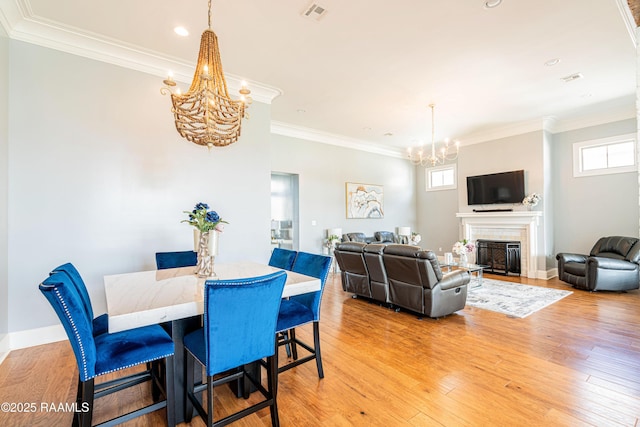 104 Peaceful Hollow Ln, Lafayette, LA 70508 - dining area with visible vents, crown molding, a fireplace, light wood finished floors, and a notable chandelier