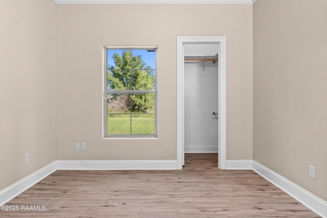1115 Jules Broussard Rd, Breaux Bridge, LA 70517 - unfurnished bedroom with multiple windows, a walk in closet, and light wood-type flooring