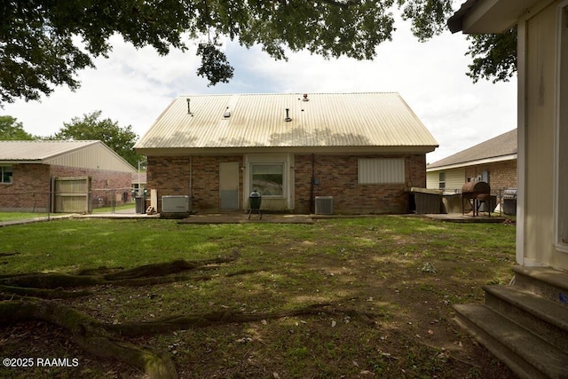 118 Fraternity Dr, Lafayette, LA 70506 - back of house featuring metal roof, brick siding, central AC, fence, and a yard