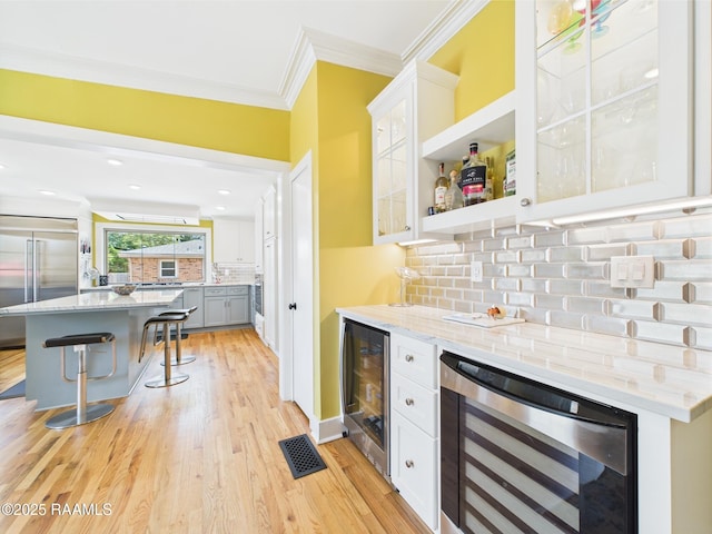 bar featuring crown molding, beverage cooler, appliances with stainless steel finishes, and a bar