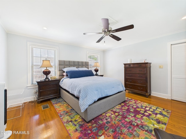 bedroom featuring visible vents, ornamental molding, and wood finished floors