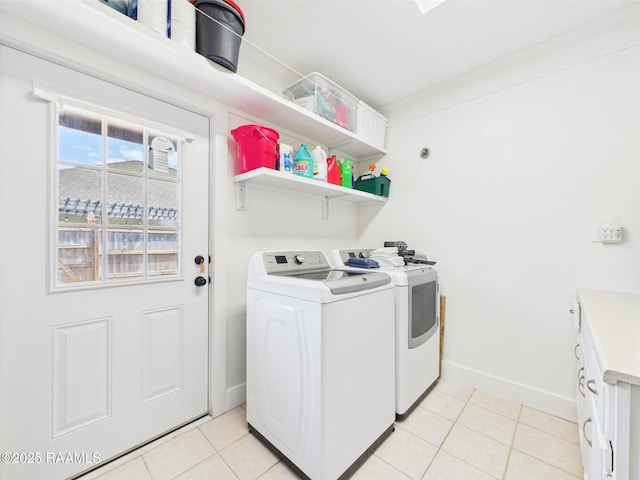 washroom featuring cabinet space, light tile patterned flooring, baseboards, and washer and clothes dryer