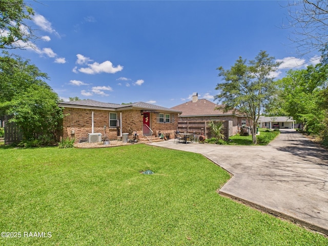 view of front of house with brick siding, a chimney, a front yard, and entry steps