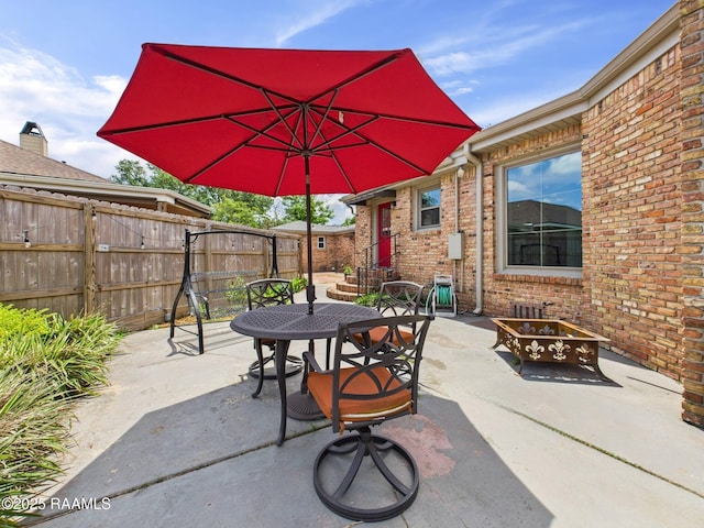 view of patio / terrace with fence, outdoor dining space, and an outdoor fire pit