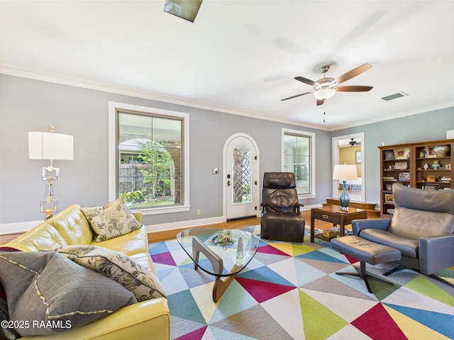 living area featuring ceiling fan, visible vents, crown molding, wood finished floors, and baseboards