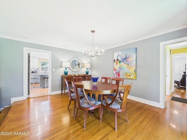 dining area with crown molding, baseboards, light wood-style floors, and a chandelier