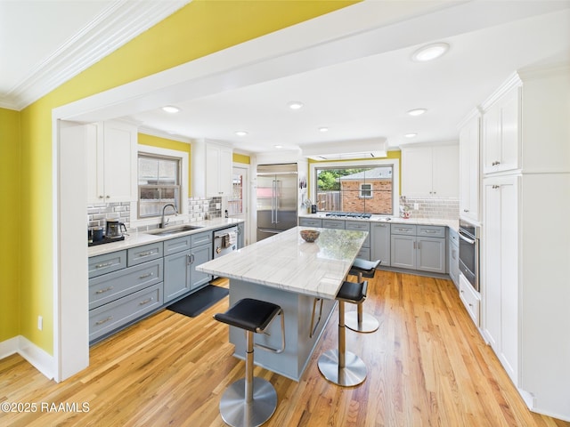 kitchen featuring crown molding, a sink, appliances with stainless steel finishes, and gray cabinetry