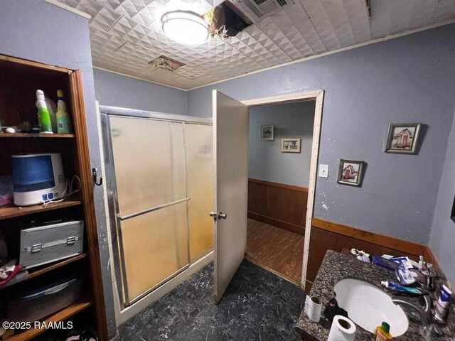 full bathroom featuring visible vents, a shower stall, a sink, a wainscoted wall, and wooden walls