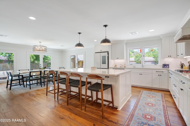 1022 Roselawn Dr, Lafayette, LA 70503 - kitchen with fridge, a center island, light countertops, white cabinetry, and backsplash