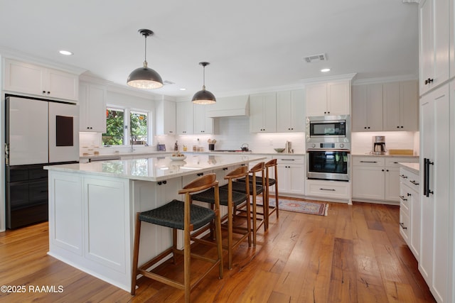 1022 Roselawn Dr, Lafayette, LA 70503 - kitchen with visible vents, decorative backsplash, light wood-style floors, white cabinets, and appliances with stainless steel finishes