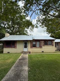 ranch-style home with metal roof and a front lawn