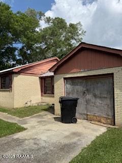 view of side of property with brick siding, a garage, and driveway