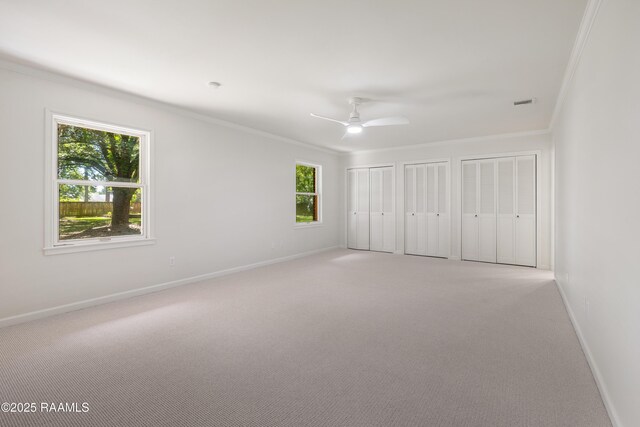 201 W Eleanor St, Opelousas, LA 70570 - unfurnished bedroom featuring two closets, multiple windows, light colored carpet, ornamental molding, and ceiling fan