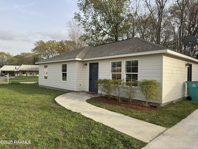 ranch-style home with a shingled roof and a front lawn