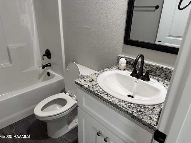 full bath with vanity, a textured wall, bathtub / shower combination, and toilet