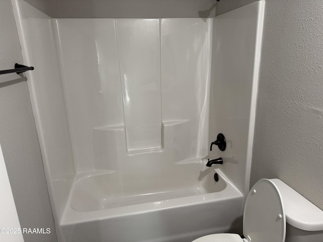 bathroom featuring a textured wall and toilet