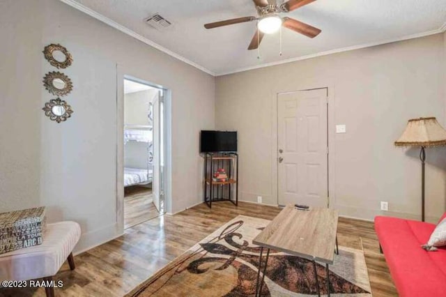 living room with visible vents, a ceiling fan, crown molding, and wood finished floors